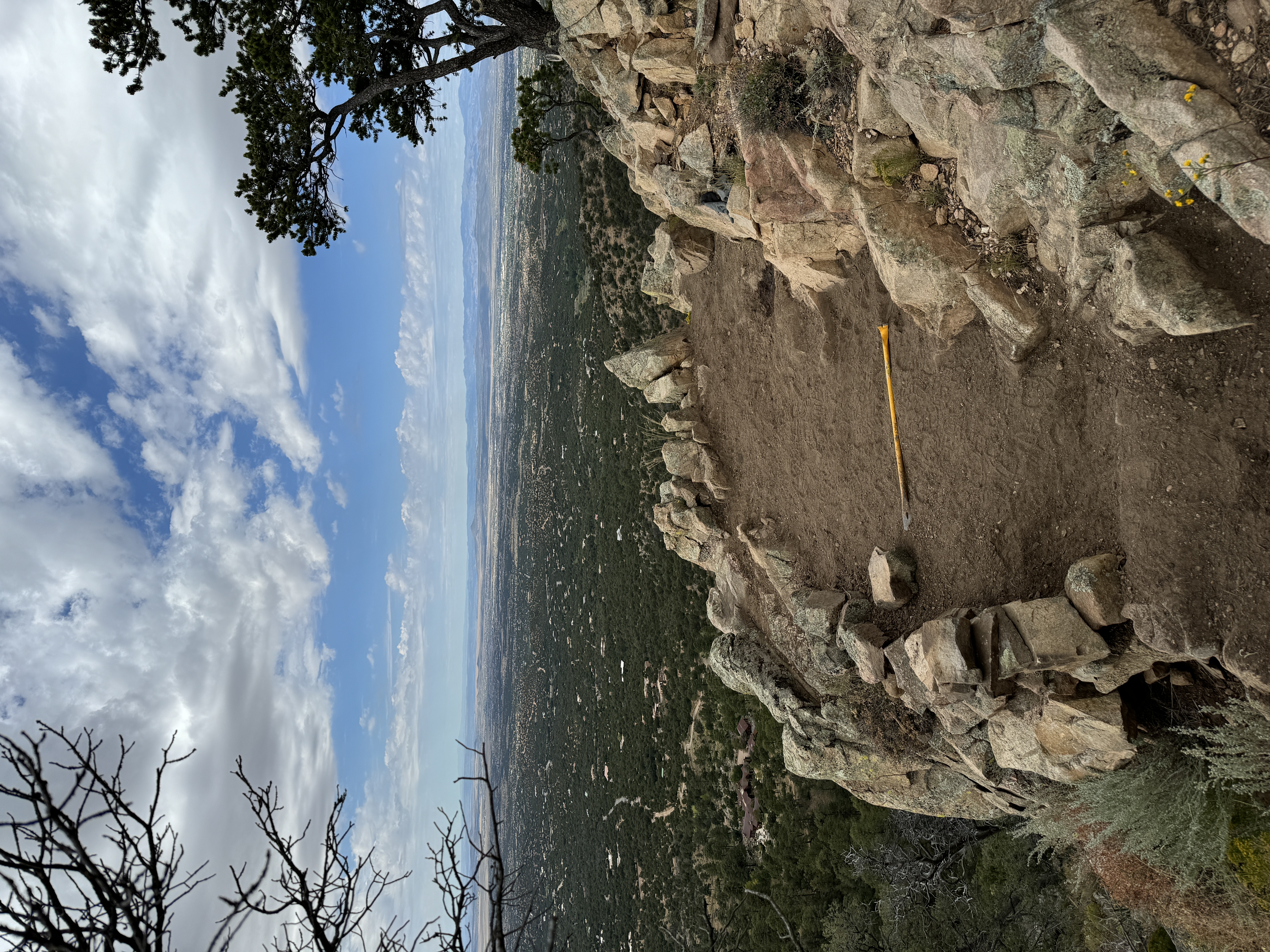 Stone terrace with pickaxe — mountain views, cloudy sky